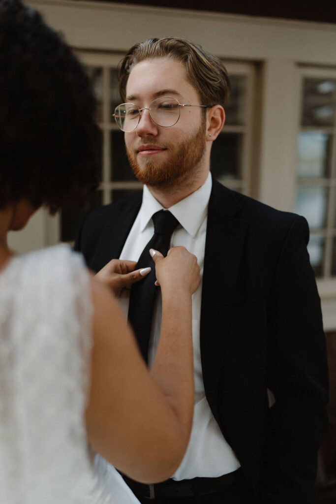 bride helping the groom with his tuxedo