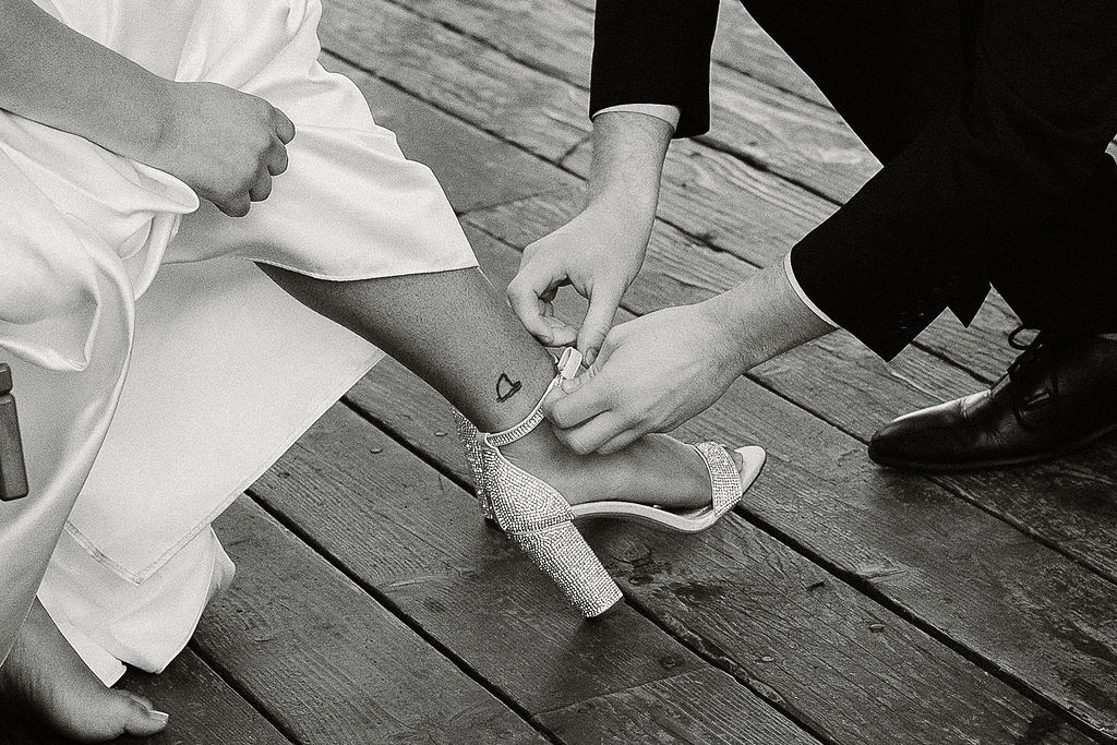 groom helping the bride put on her shoes