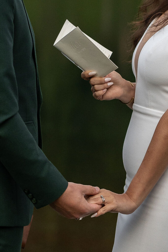 couple holding hands reading their vows