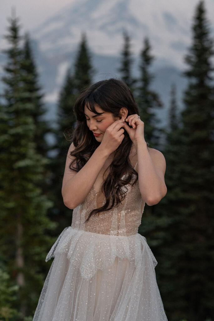 bride putting on her jewelry for her elopement ceremony 